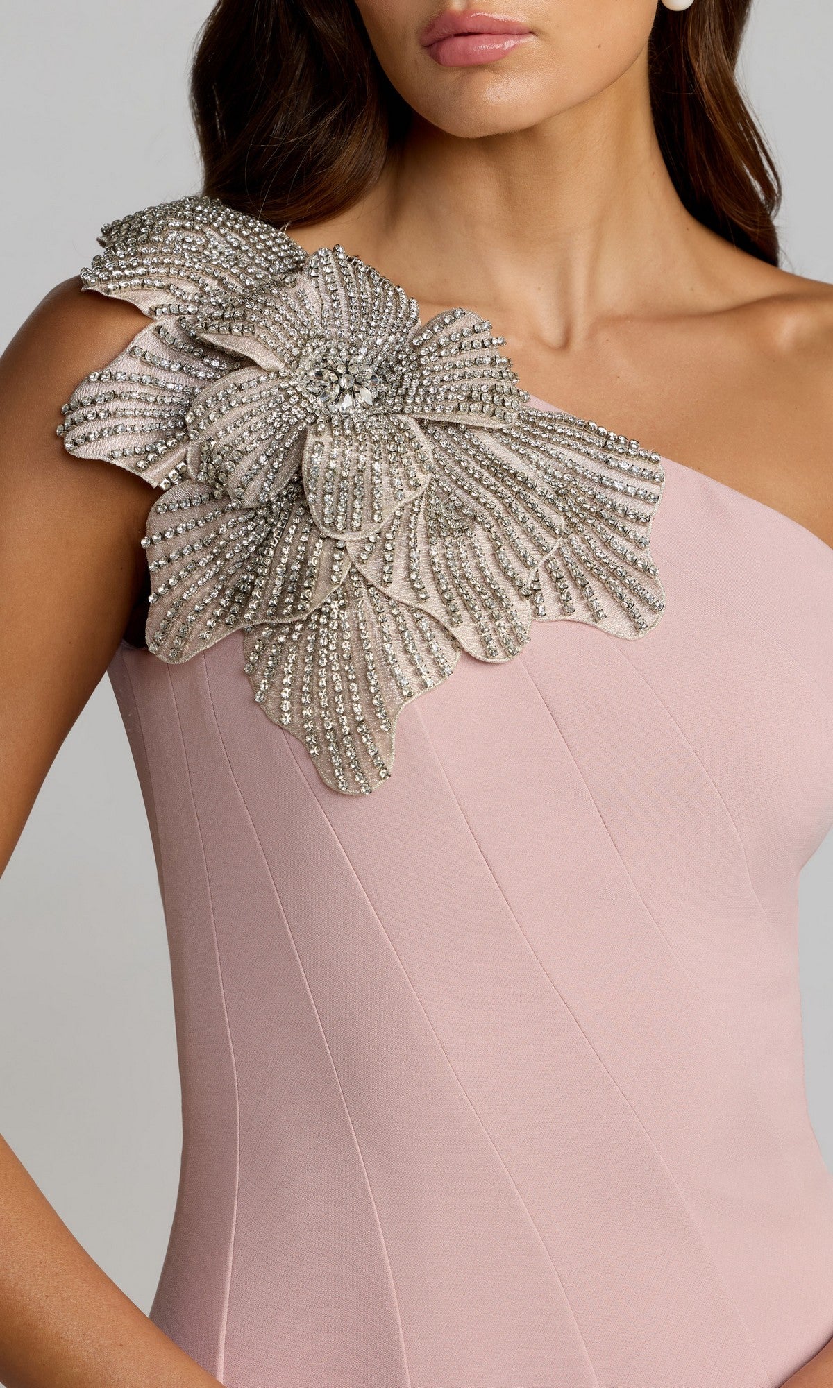 Woman wearing the Mac Duggal 11810 Beaded-One-Shoulder Prom Gown in pale pink, featuring a striking silver beaded floral embellishment on the single shoulder.